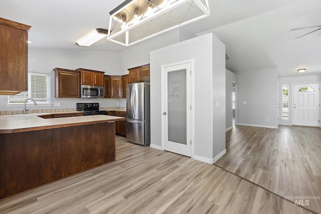 1030 Caswell Ave W, Twin Falls, ID 83301 - kitchen featuring stainless steel appliances, vaulted ceiling, light wood-style flooring, a peninsula, and light countertops