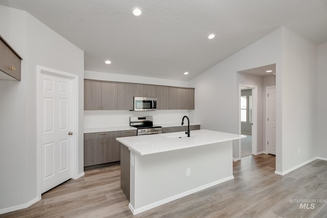 kitchen featuring stainless steel appliances, sink, a center island with sink, and light hardwood / wood-style flooring