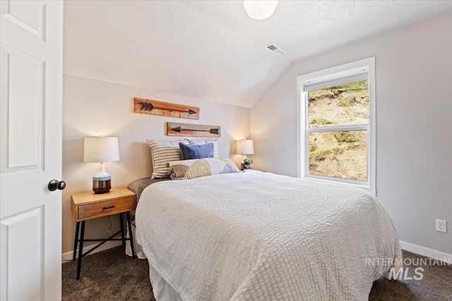 bedroom with dark colored carpet, lofted ceiling, and baseboards