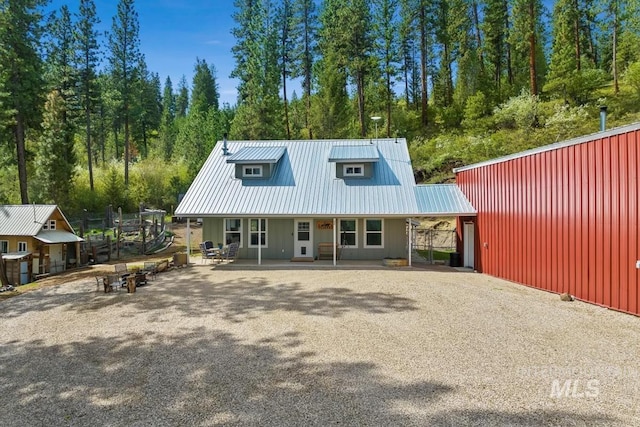 view of front facade with gravel driveway, metal roof, and an outdoor structure