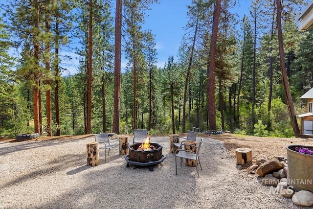 view of patio with a fire pit and a view of trees