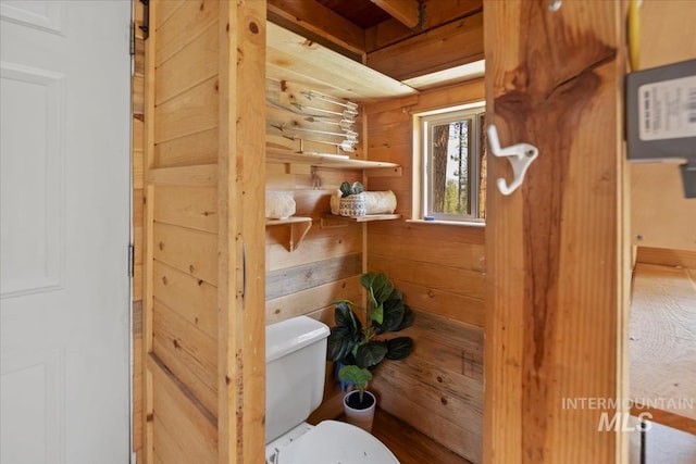 bathroom featuring toilet and wooden walls