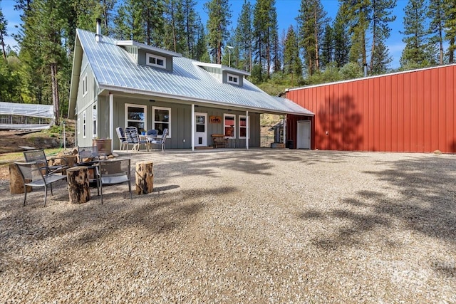 view of front of property with board and batten siding, metal roof, a fire pit, and a porch