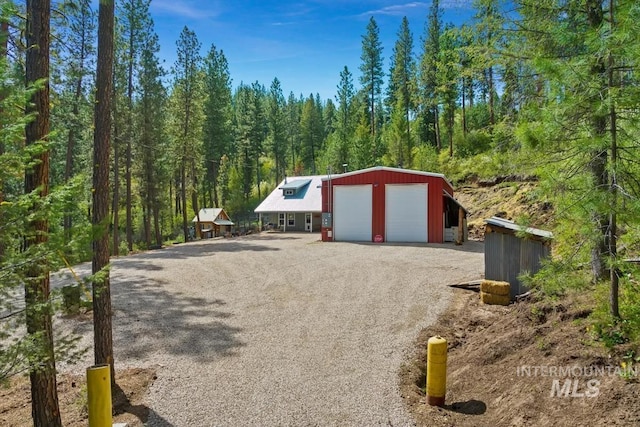 detached garage featuring a view of trees and driveway
