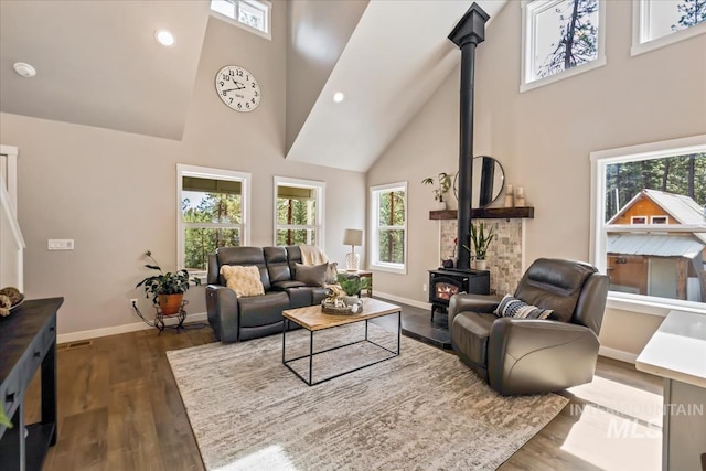 living area featuring high vaulted ceiling, a wood stove, baseboards, wood finished floors, and recessed lighting