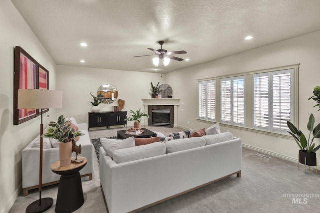 carpeted living area with visible vents, baseboards, a fireplace with flush hearth, recessed lighting, and a ceiling fan