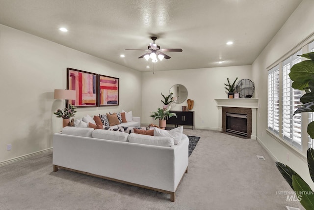 living room featuring a ceiling fan, baseboards, a fireplace with flush hearth, recessed lighting, and light carpet