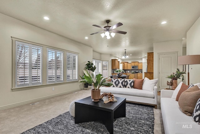 carpeted living area featuring visible vents, baseboards, ceiling fan, recessed lighting, and a textured ceiling