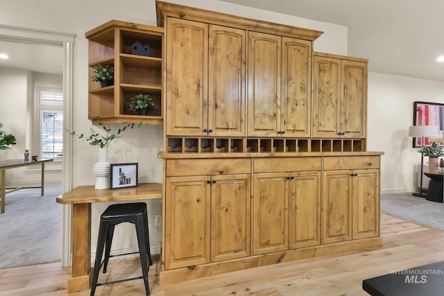 kitchen featuring open shelves, light wood-style floors, baseboards, and light colored carpet