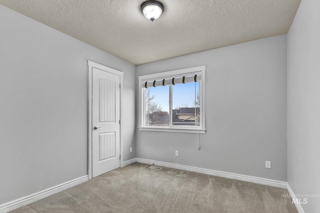 empty room with carpet flooring, a textured ceiling, and baseboards