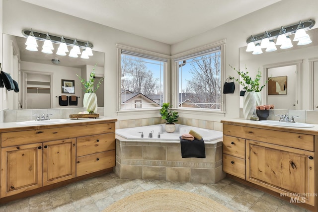 full bathroom featuring two vanities, a bath, and a sink