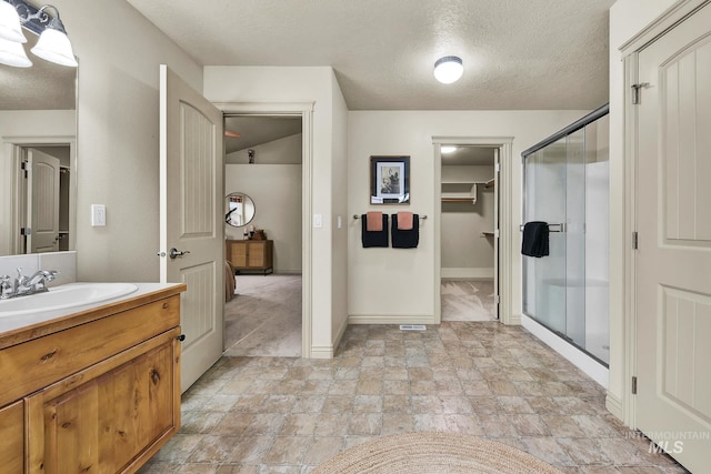 full bathroom with baseboards, vanity, a shower stall, and a textured ceiling