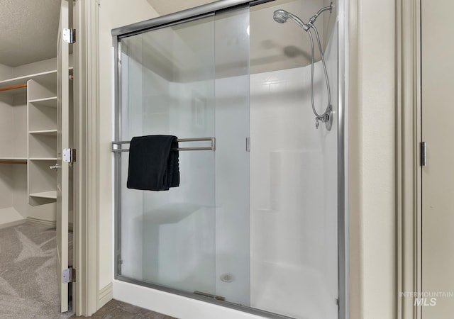 bathroom featuring a spacious closet, a stall shower, and a textured ceiling