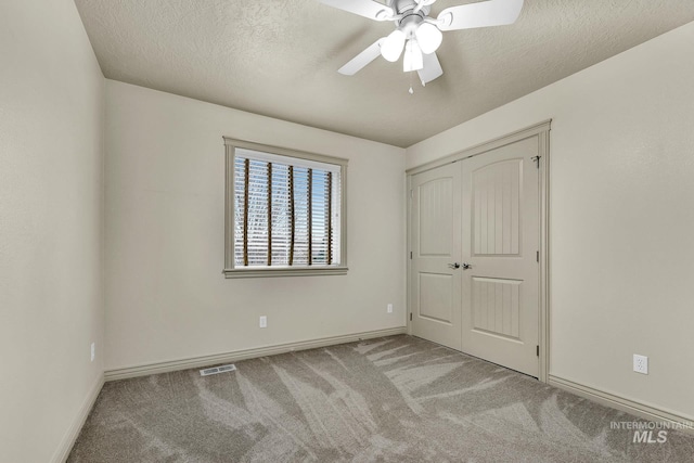 unfurnished bedroom with visible vents, carpet floors, a textured ceiling, and ceiling fan