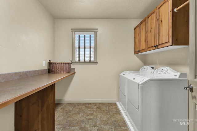 laundry area featuring baseboards, washing machine and clothes dryer, cabinet space, stone finish flooring, and a textured ceiling