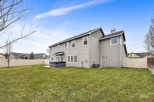 back of house featuring central air condition unit, a yard, a fenced backyard, and a hot tub