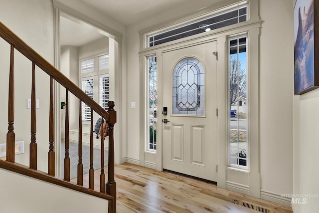 foyer entrance with visible vents, stairway, and light wood-style floors