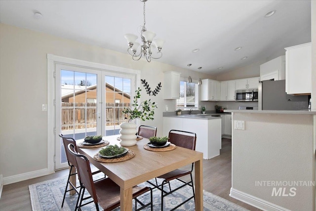 dining area with lofted ceiling, a chandelier, and light hardwood / wood-style flooring