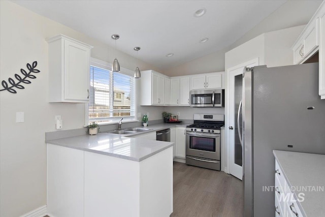 kitchen with appliances with stainless steel finishes, pendant lighting, sink, white cabinets, and kitchen peninsula