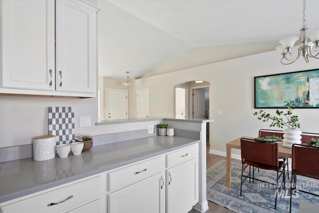 kitchen featuring white cabinetry, wood-type flooring, vaulted ceiling, hanging light fixtures, and kitchen peninsula