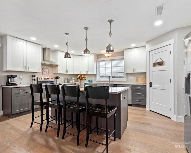 kitchen with a breakfast bar area, a center island, white cabinetry, and hanging light fixtures