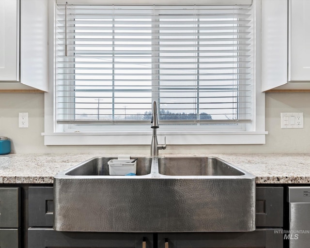 details with white cabinets, light stone countertops, and sink