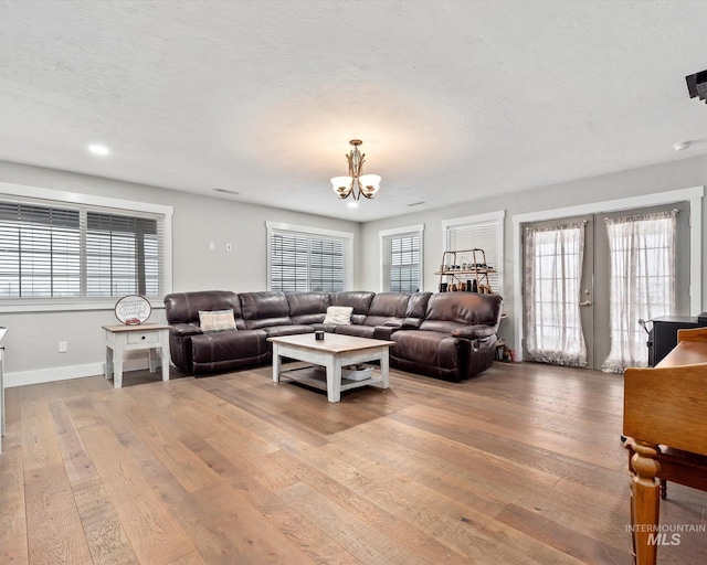 living room with french doors, a chandelier, and light hardwood / wood-style flooring