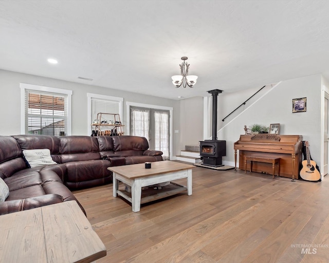 living room featuring a chandelier, a wood stove, and light wood-type flooring