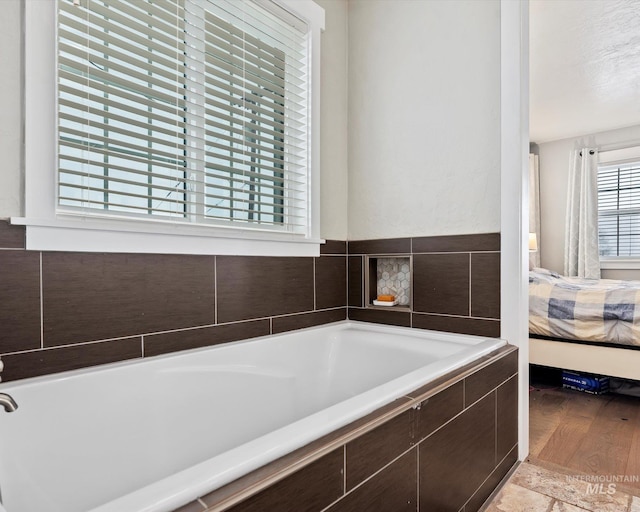 bathroom with a textured ceiling and a relaxing tiled tub