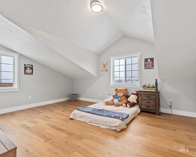 bedroom with hardwood / wood-style flooring, a textured ceiling, and vaulted ceiling