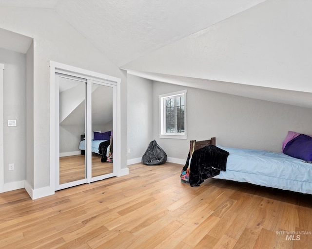 bedroom with light wood-type flooring and lofted ceiling