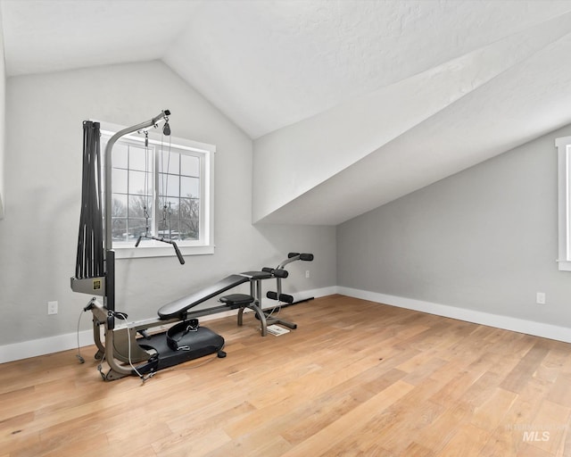 exercise room featuring wood-type flooring and vaulted ceiling