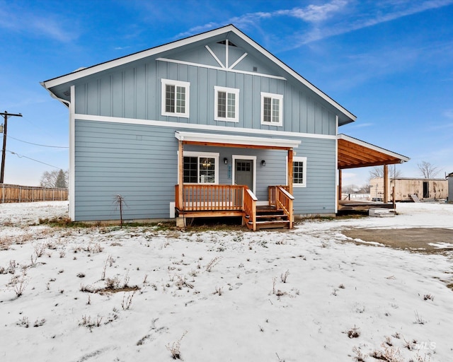 snow covered back of property with covered porch