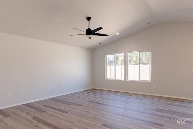spare room with lofted ceiling, a ceiling fan, baseboards, and light wood-style flooring