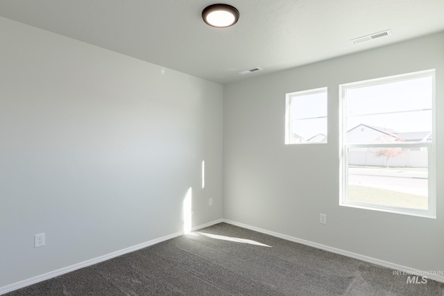 unfurnished room featuring dark carpet, baseboards, and visible vents