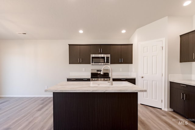 kitchen featuring stainless steel appliances, dark brown cabinets, visible vents, light wood-style floors, and light countertops