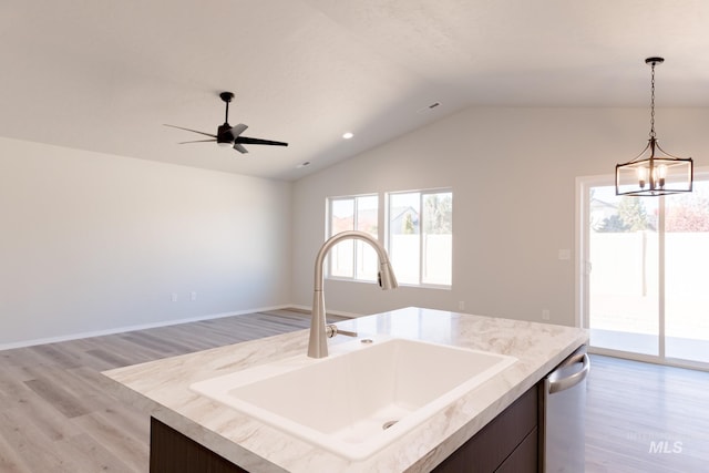 kitchen featuring light wood-type flooring, dishwasher, a sink, and hanging light fixtures