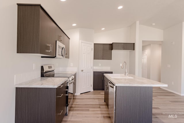 kitchen featuring light wood finished floors, stainless steel appliances, light countertops, and a sink