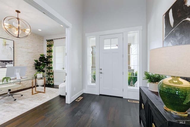 foyer entrance with dark wood-style floors, a chandelier, plenty of natural light, baseboards, and a high ceiling