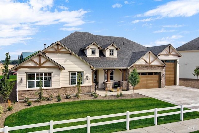 view of front of property with covered porch, a garage, driveway, stone siding, and a shingled roof