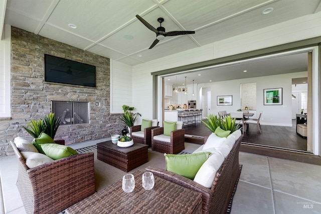 view of patio with an outdoor living space with a fireplace, outdoor dining space, and a ceiling fan