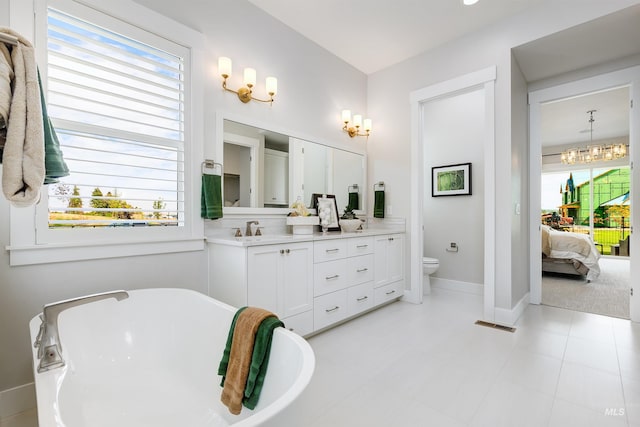 ensuite bathroom featuring toilet, a freestanding bath, plenty of natural light, and a chandelier