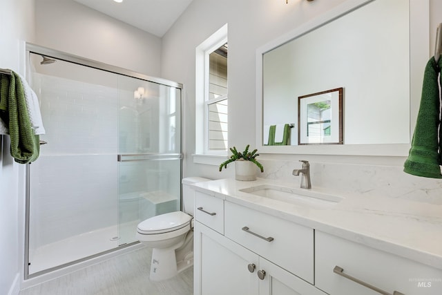 full bathroom featuring a shower stall, toilet, and vanity