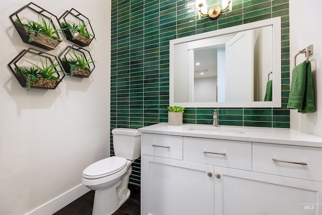 half bathroom with tile walls, toilet, vanity, and baseboards
