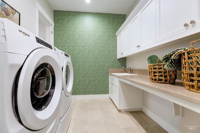 laundry room featuring an accent wall, wallpapered walls, washer and dryer, baseboards, and cabinet space