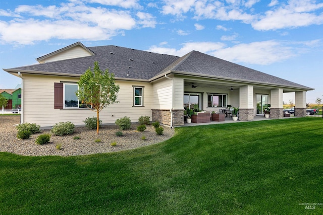 rear view of property with a ceiling fan, outdoor lounge area, a shingled roof, and a yard