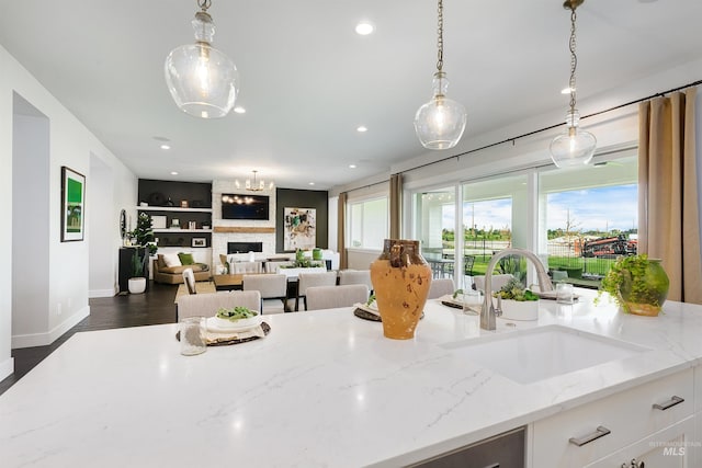 kitchen featuring a sink, decorative light fixtures, light stone counters, white cabinets, and recessed lighting