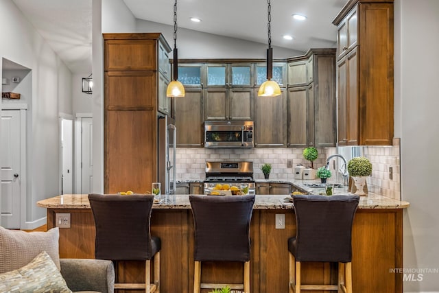2411 S Marypost, Eagle, ID 83616 - kitchen featuring appliances with stainless steel finishes, vaulted ceiling, tasteful backsplash, light stone counters, and a peninsula