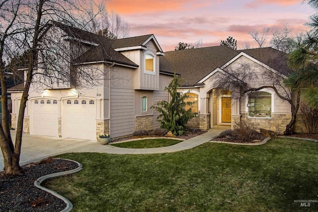 view of front of property featuring stone siding, a shingled roof, a front yard, and driveway