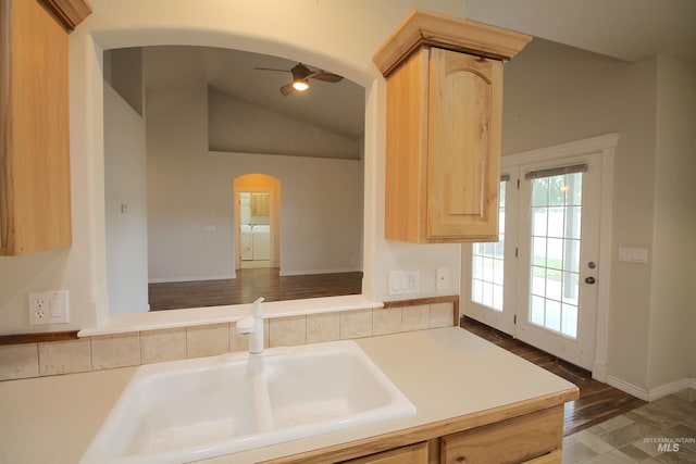kitchen with arched walkways, light brown cabinetry, a sink, ceiling fan, and lofted ceiling